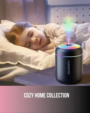 Cozy Home Collection featuring a black RGB humidifier with colorful LED lighting and mist, placed on a nightstand beside a peacefully sleeping child in a warm, cozy bedroom